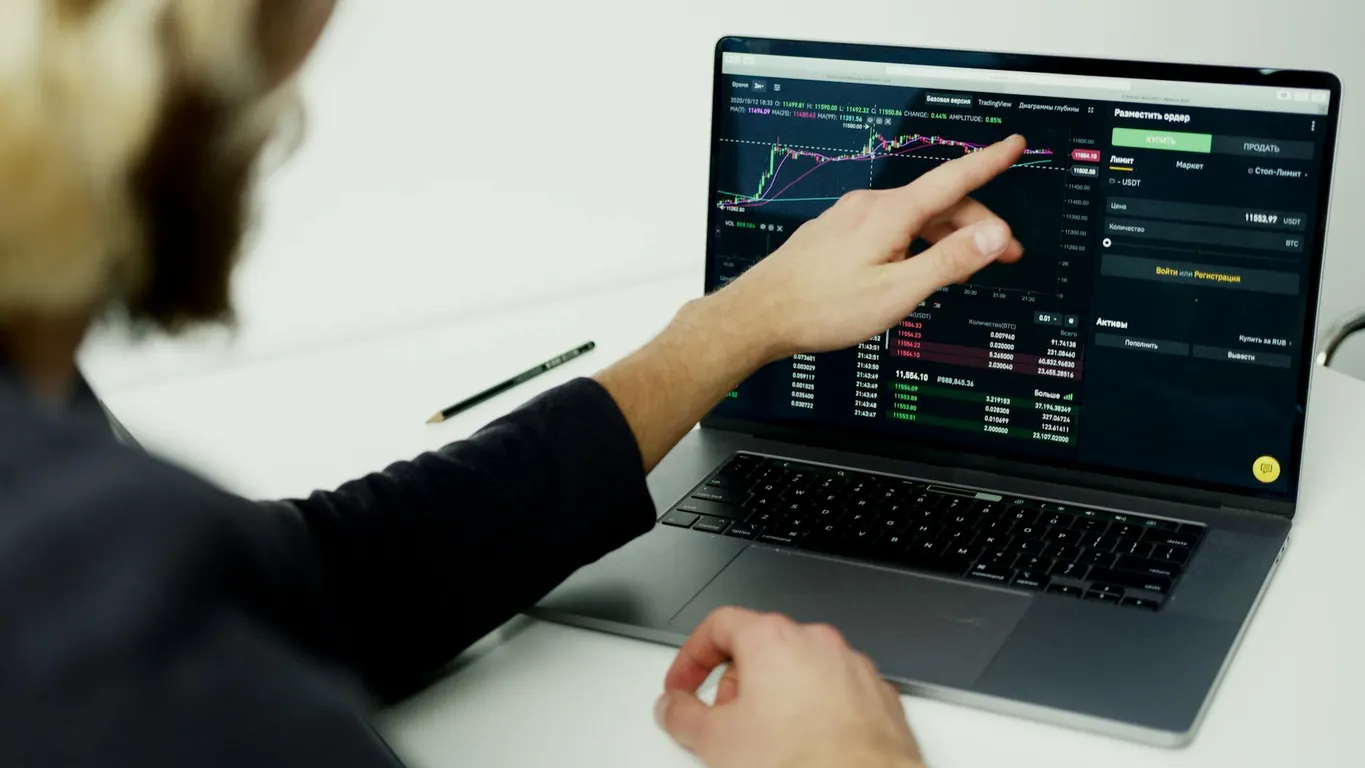 A person analyzing stock market graphs on a laptop screen