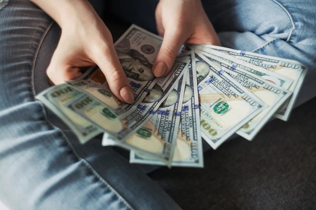 A woman holding stacks of $100 bills