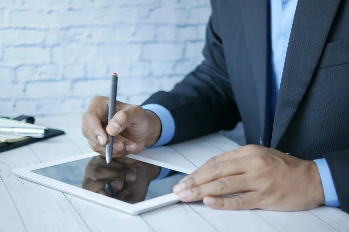 A man in a suit writing on a tablet