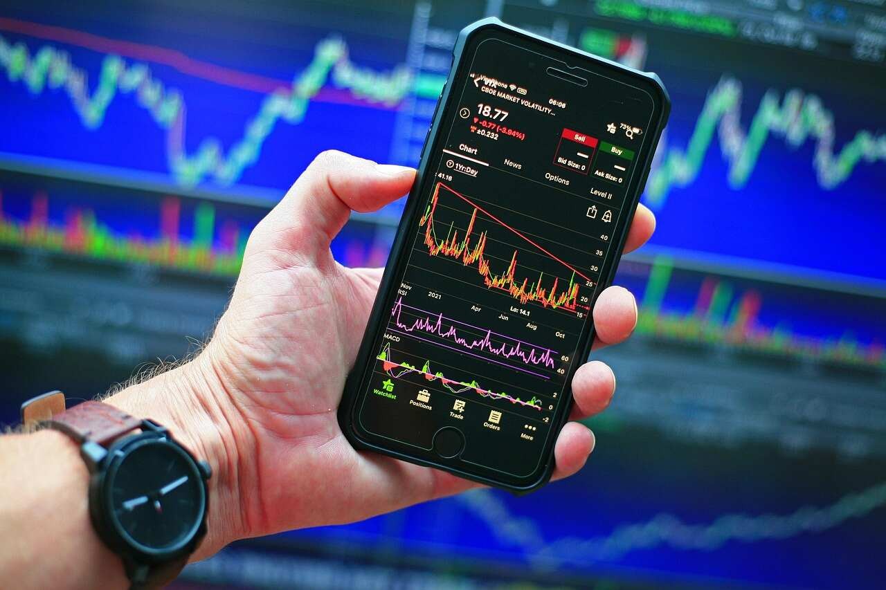 crypto app holding in hand with watch and charts in background